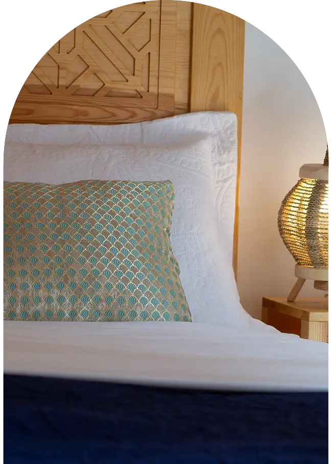 Lit marocain en bois sculpté avec linge soigné dans une chambre de riad à Essaouira