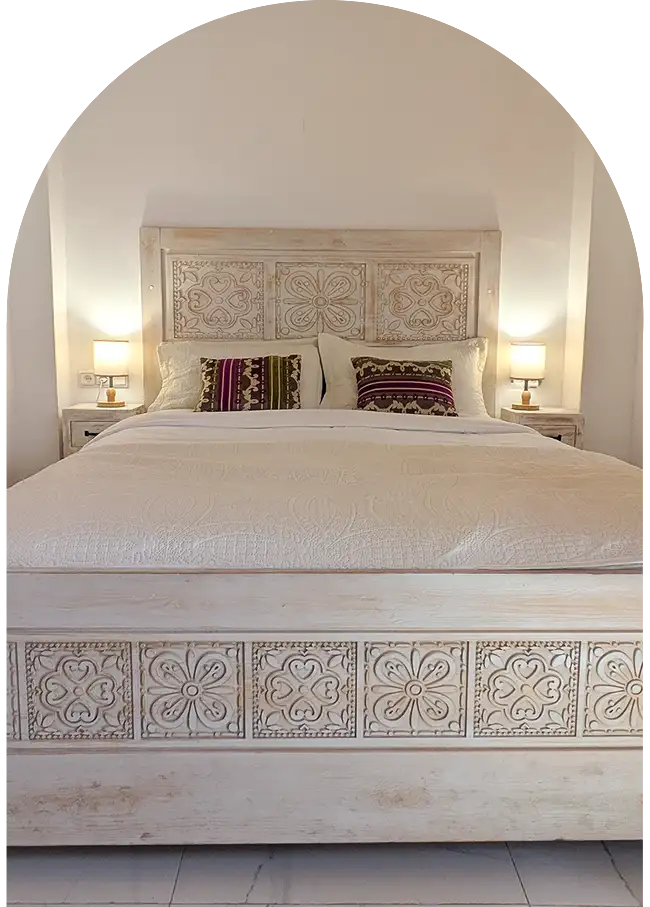 Lit double en bois sculpté avec linge raffiné dans un riad à Essaouira