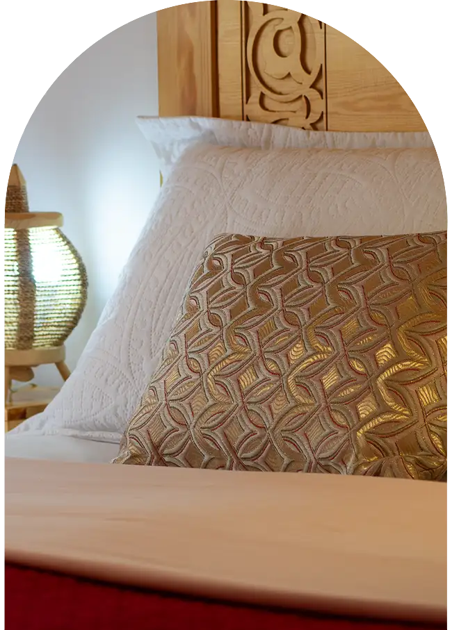 Lit marocain en bois sculpté avec linge soigné dans une chambre de riad à Essaouira