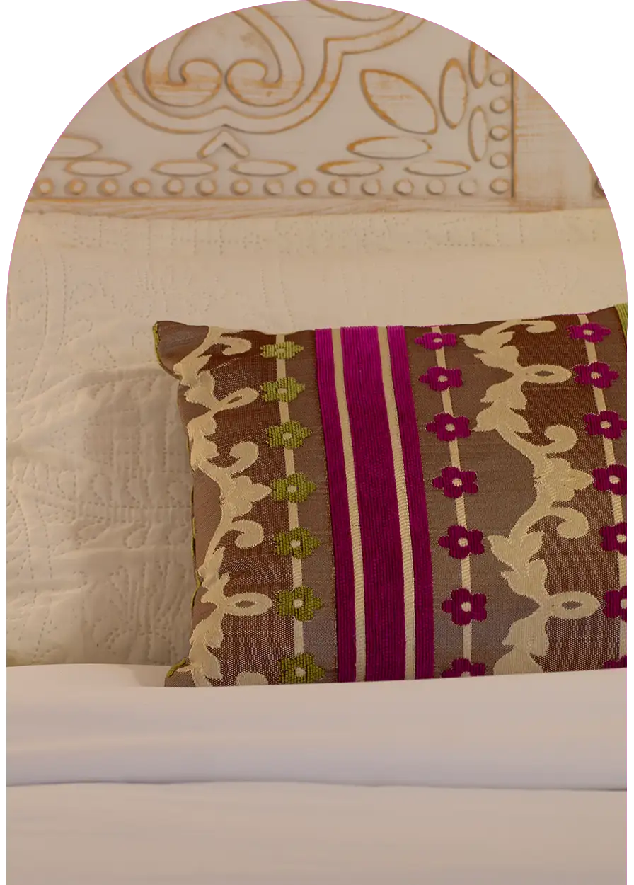Oreiller en tissu coloré et tête de lit en bois sculpté traditionnel, détail raffiné de décoration marocaine